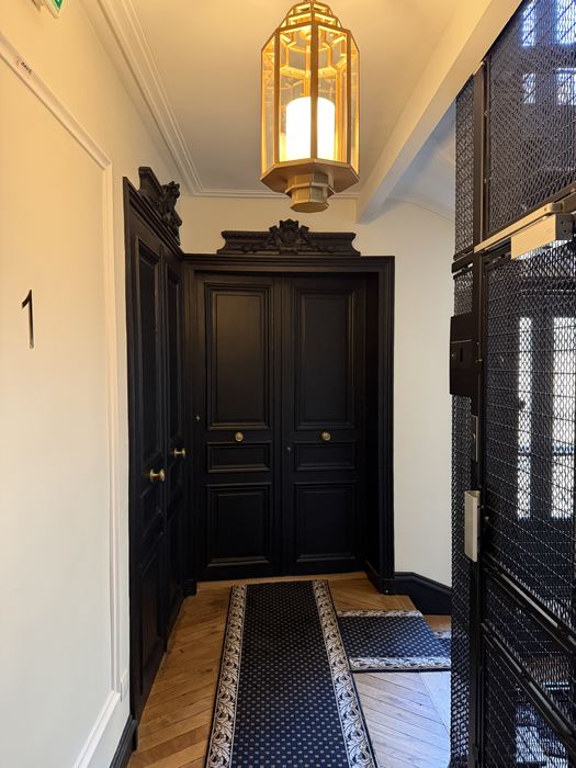Palier d'immeuble rénové avec lanterne et tapis d'escalier